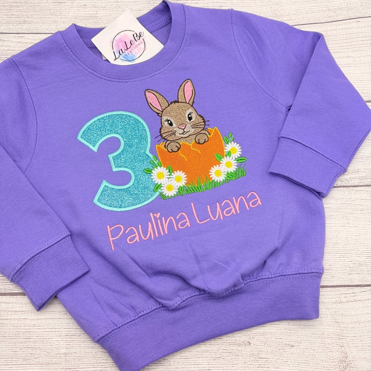 Hase Geburtstagsshirt Mädchen personalisiert – lila Sweatshirt mit Hasen im Ei, türkiser Glitzerzahl und Name