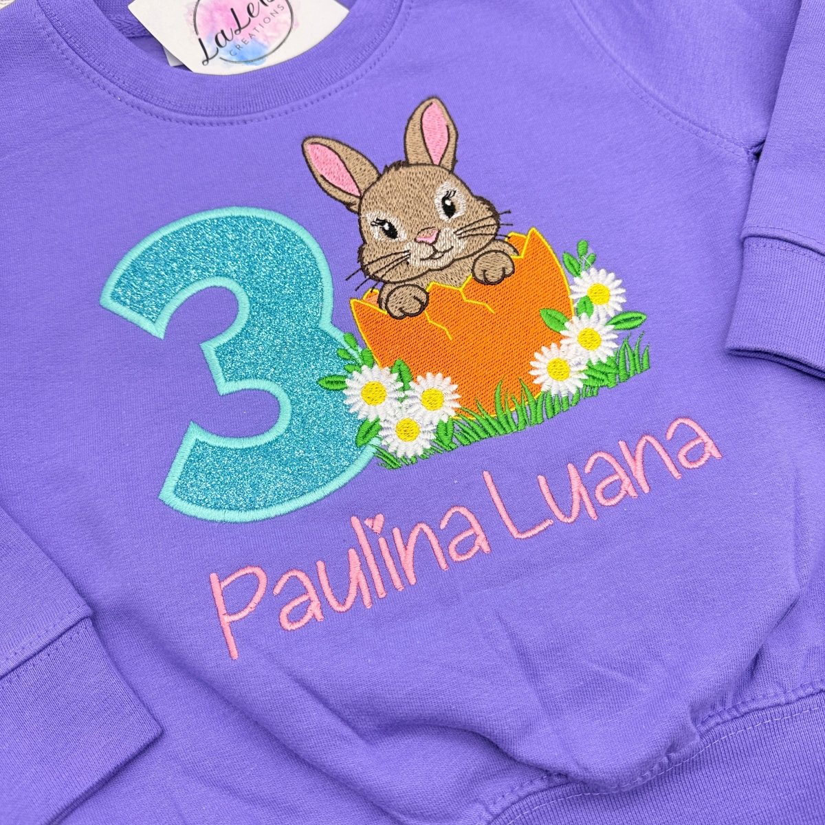 Besticktes Hase Geburtstagsshirt Mädchen – Nahaufnahme Hase im Ei mit Gänseblümchen und Glitzerzahl – LaLeBe Creations